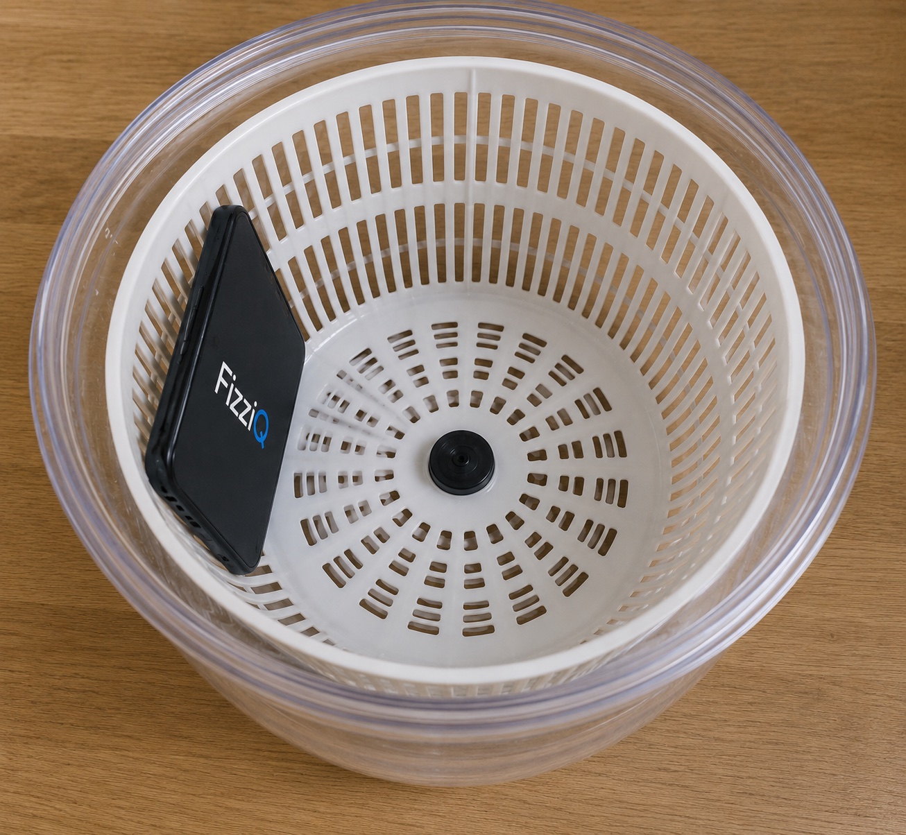 Smartphone calé dans le panier d'une essoreuse à salade transparente, vu de dessus : le dispositif fait tourner l'appareil à rayon connu pour mesurer l'accélération centripète.