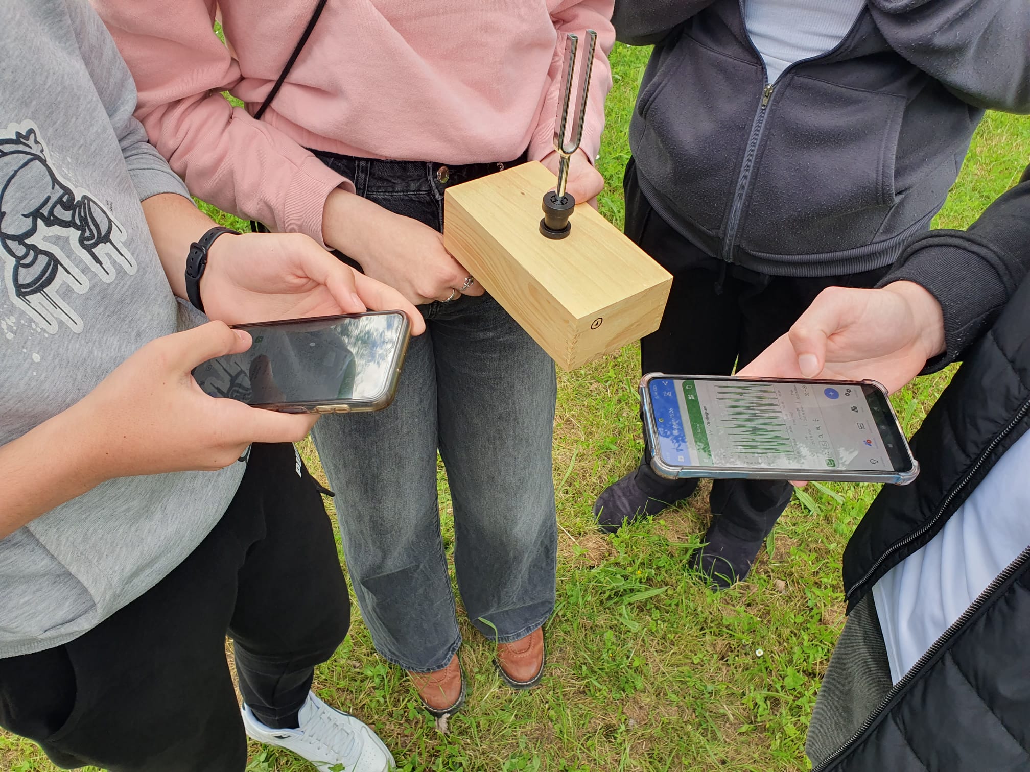 Élèves étudiant un diapason avec un smartphone affichant un oscillogramme